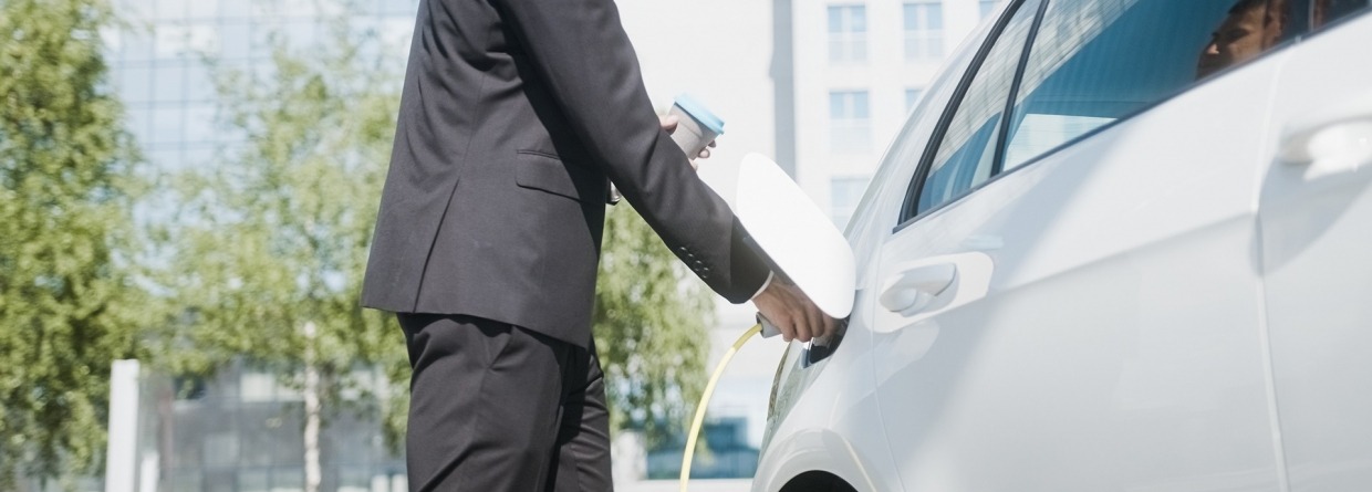Zakenman laad elektrische auto op op zijn werk